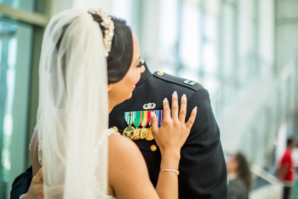 A bride and groom sharing a moment, with military uniform and medals highlighted indoors.